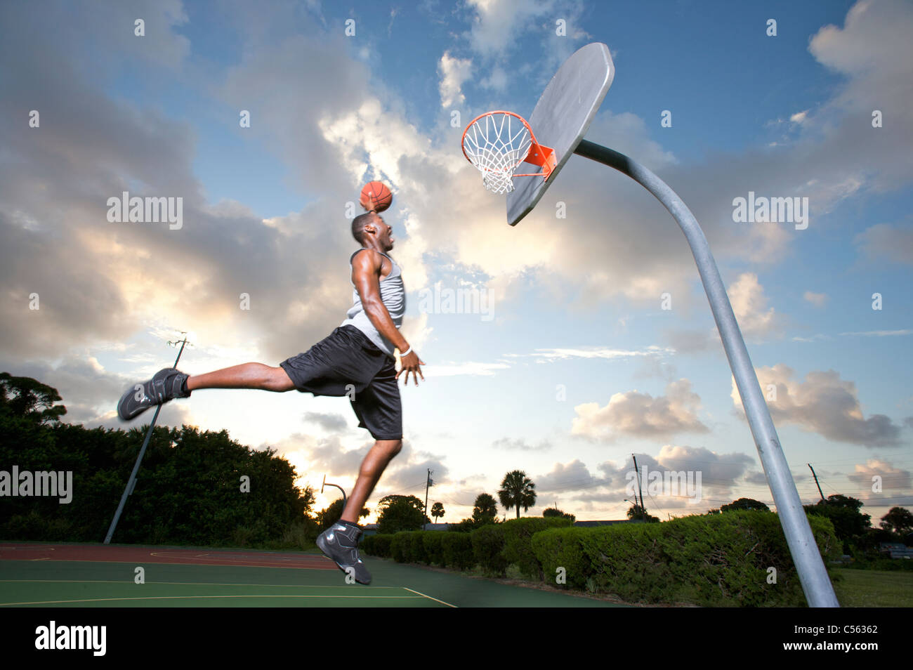 männliche machen Slam Dunk an Outdoor-Basketball-Ziel Stockfoto