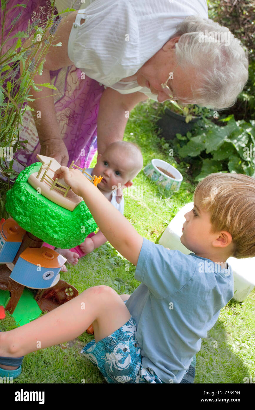Oma und die Kinder spielen draußen im Garten im Sommer Stockfoto