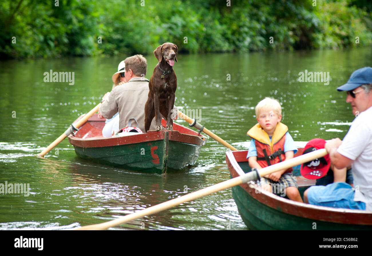 Leute, die Spaß auf dem Fluss Wey Navigationen in der Nähe von Godalming, Surrey, UK. Ein Hund wacht. Stockfoto