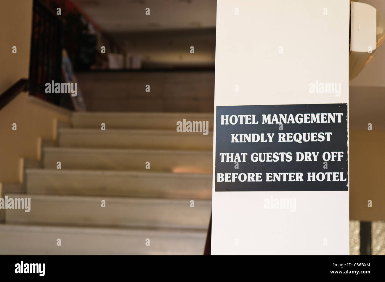 Melden Sie sich in einem Hotel Fragen Gäste sicherzustellen, dass sie sich trocknen, bevor Sie das Hotel betreten Stockfoto