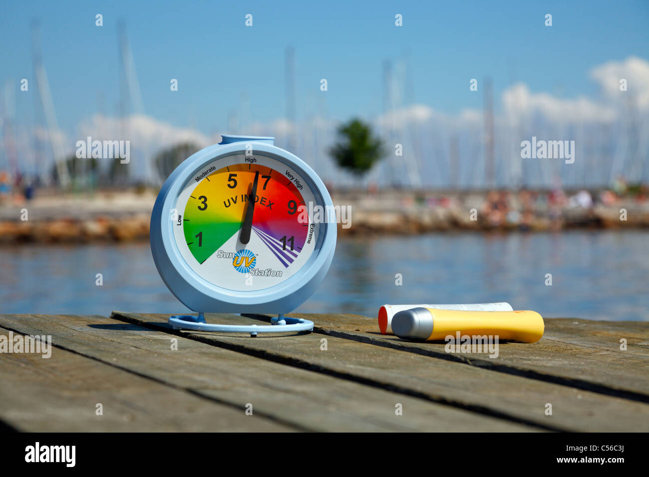 Hohe Sonne UV-Index auf einem sonnigen Nachmittag im Juli auf einem Bootssteg am Strand lesen. Die empfohlenen Sonnenschutz ist zur hand. Stockfoto