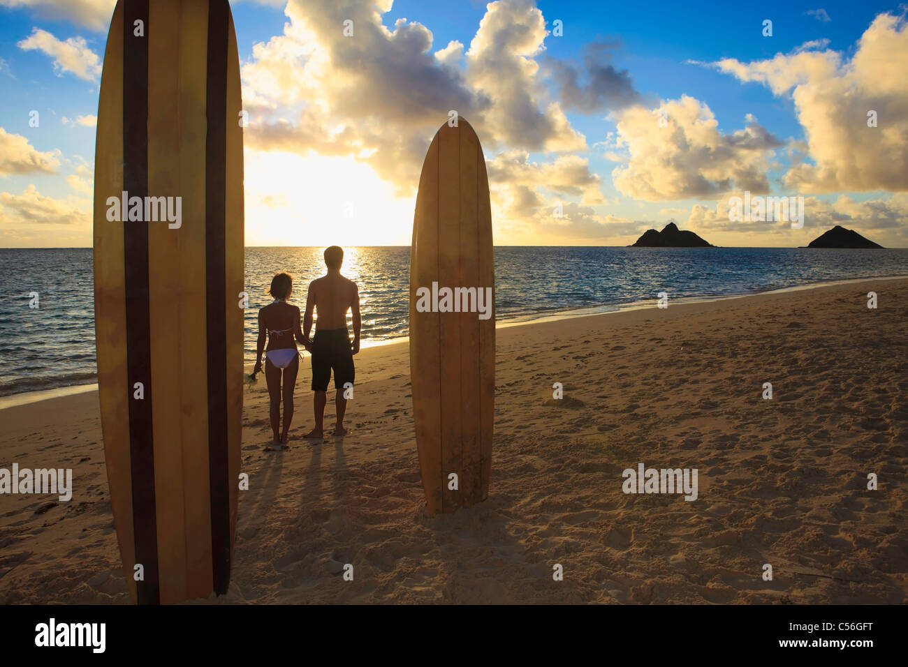 paar am Strand mit ihren Surfbrettern bei Sonnenaufgang in hawaii Stockfoto