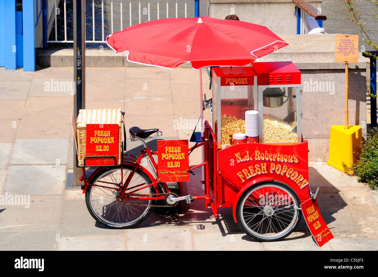 Rot Sonnenschirm über frisches Popcorn Verkäufer Dreirad montiert Maschine laufendes Geschäft für Besucher der Southbank Centre neben Themse London UK Stockfoto