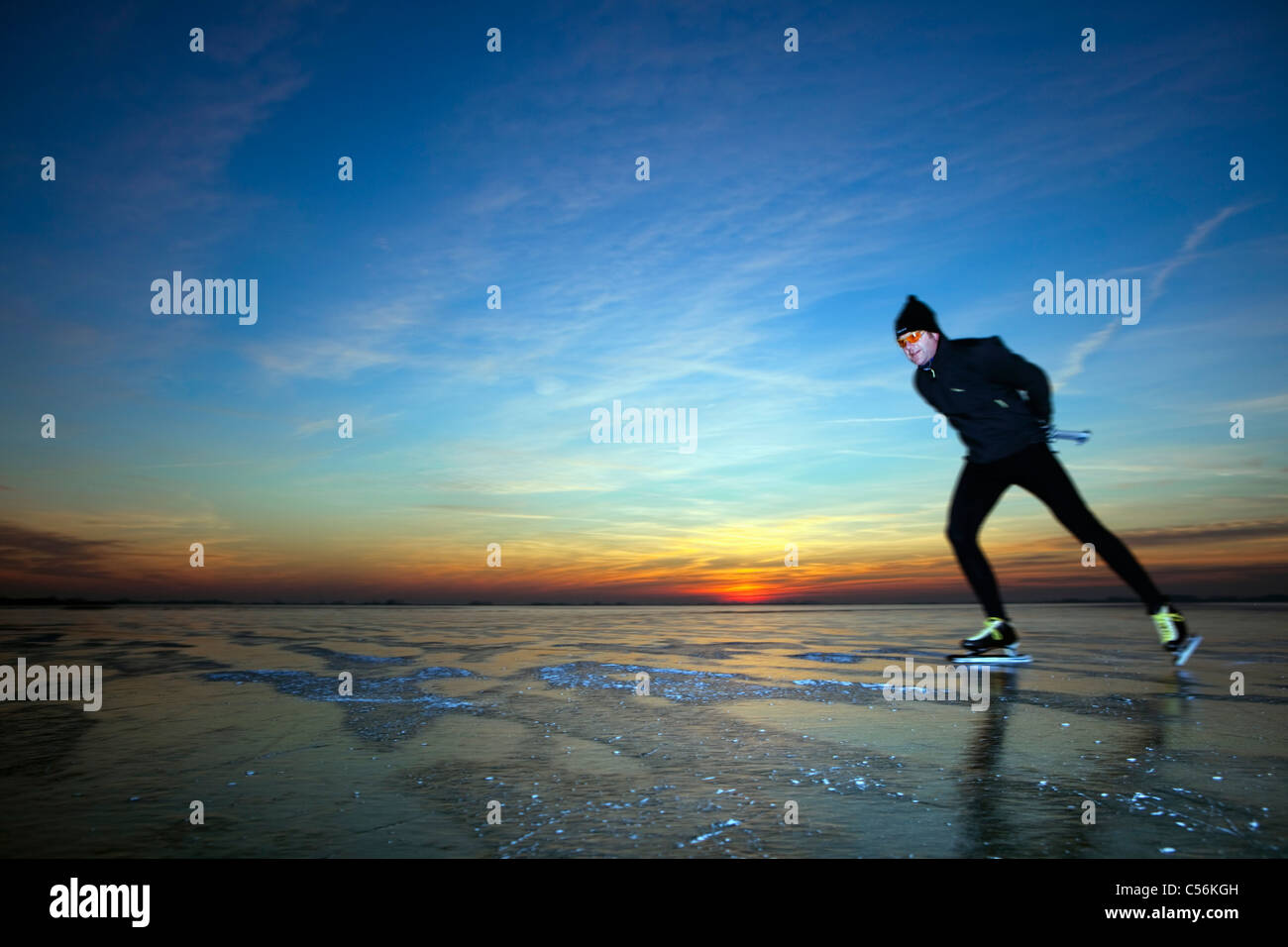 Der Niederlanden, Marken, zugefrorenen See IJsselmeer genannt. Sonnenuntergang. Man Eislaufen. Stockfoto