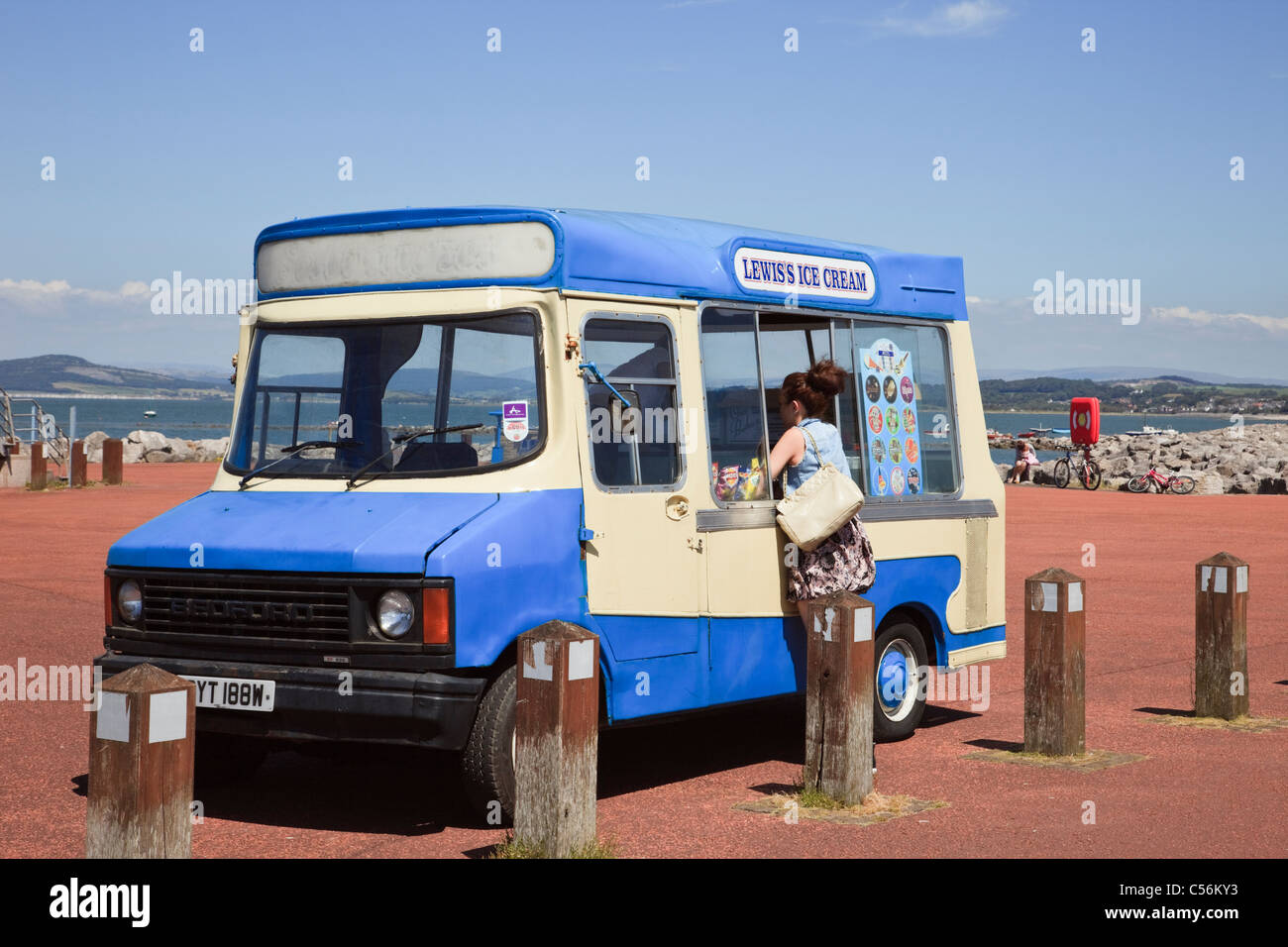 Frau kaufen Eis von einem van auf der Strandpromenade am Meer geparkt. Morecambe, Lancashire, England, Großbritannien Stockfoto
