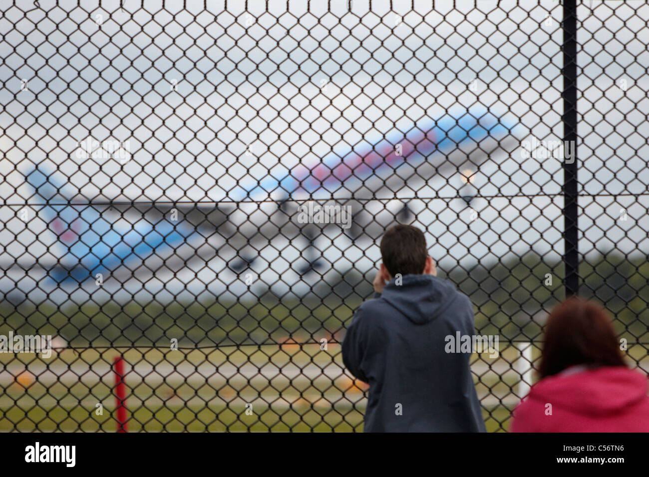 Menschen, die gerade ein Flugzeug durch einen Zaun ausziehen Stockfoto