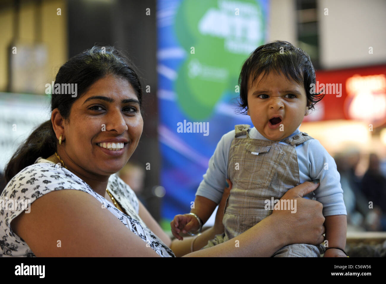 Glücklich lächelnd britischen Sikh Mutter ihr junges Baby hält, während im Einkaufszentrum West Bromwich Gähnen Stockfoto