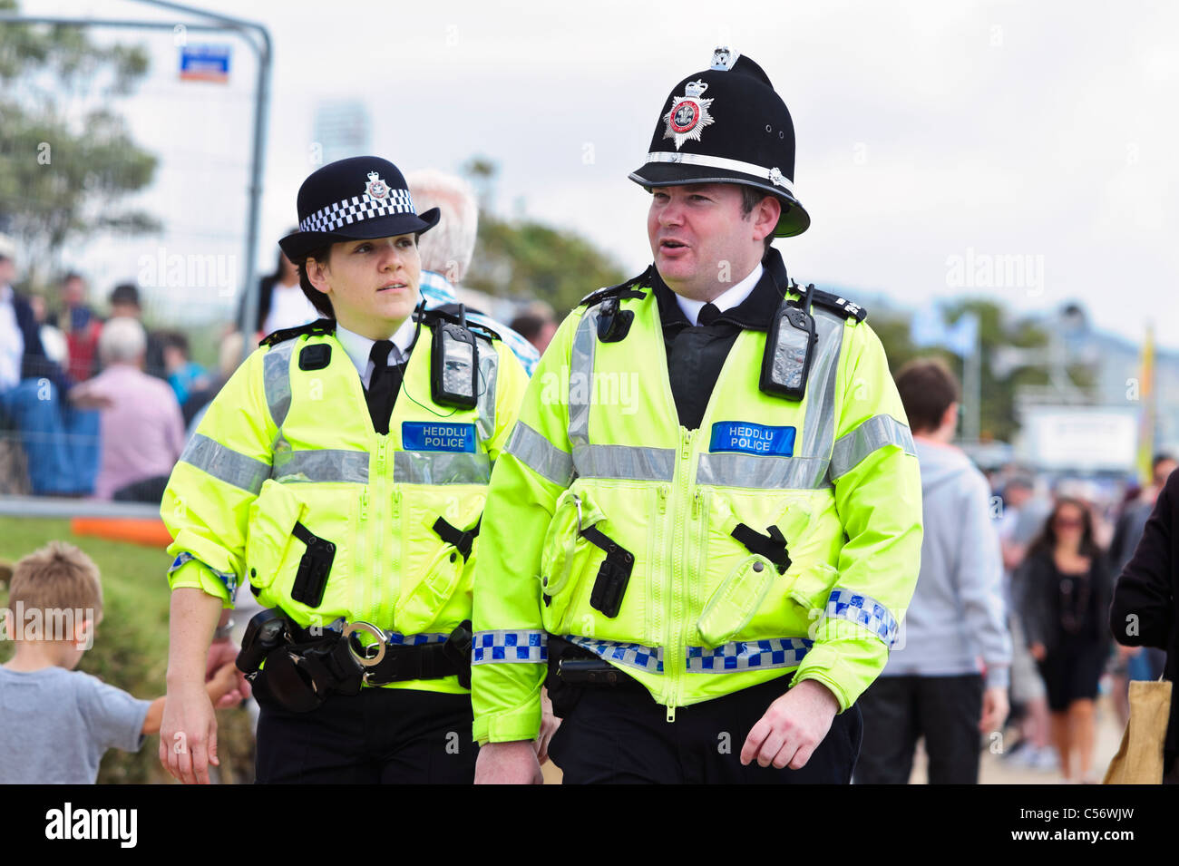 Zwei Polizisten patrouillieren im Takt, National Air show, Swansea, Wales, UK. Polizistin & Mann Heddlu Walisisch Polizei zu Fuß. Stockfoto