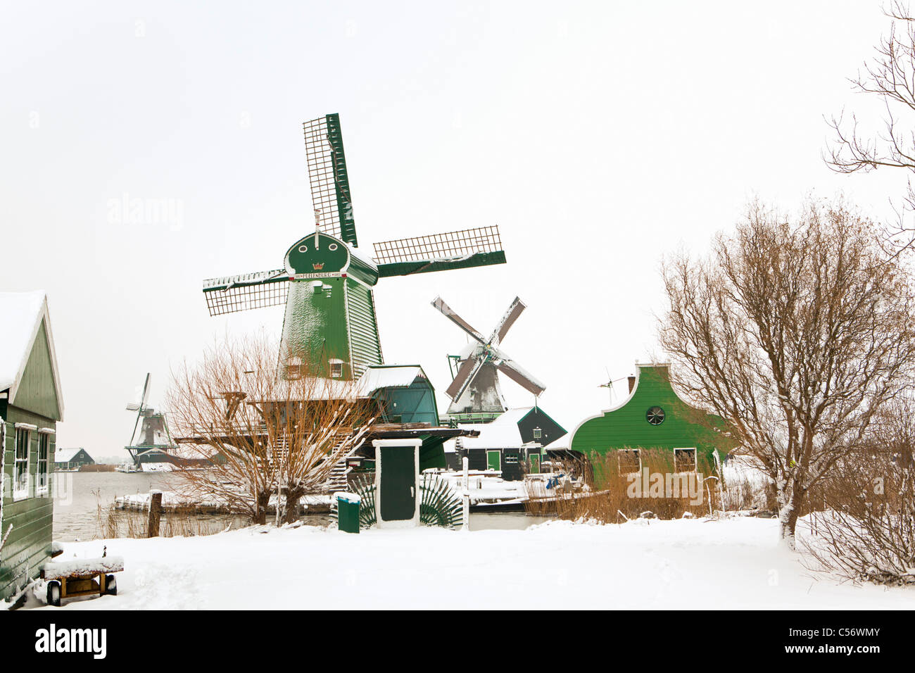 Zaanse Schans, Dorf an den Ufern des Flusses Zaan mit charakteristischen grünen hölzernen Häuser, historische Windmühlen. Winter, Schnee. Stockfoto