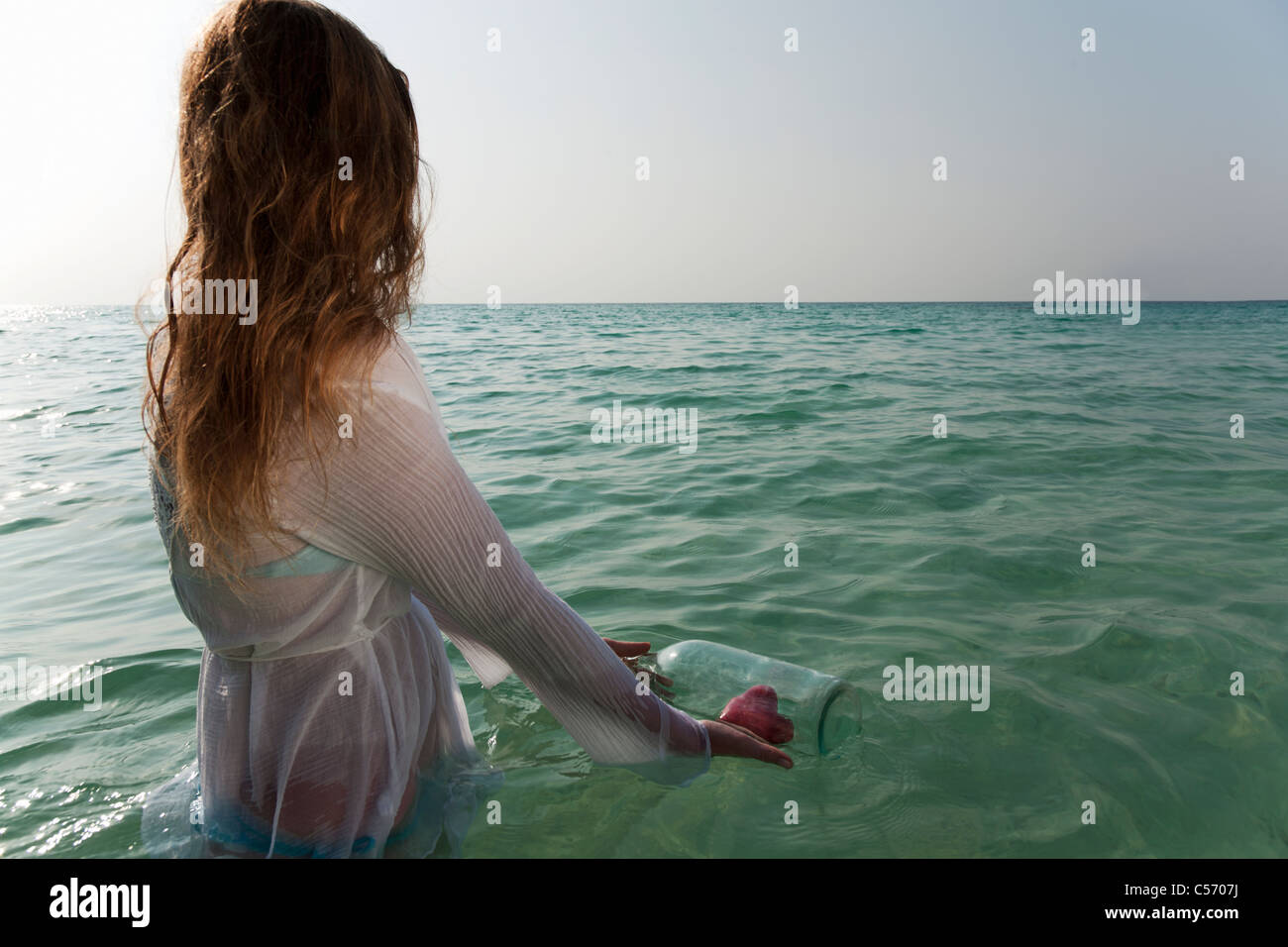 Frau im Meer mit Flaschenpost Stockfoto