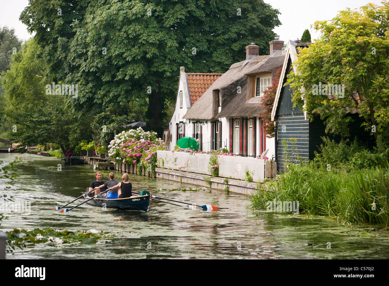 Niederlande,'s-Graveland. Menschen im Ruderboot vor alten Bauernhof. Stockfoto