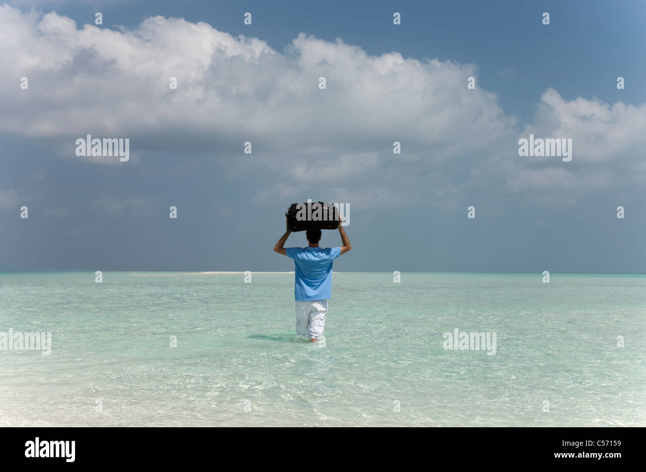 Mann mit Gepäck ins Wasser am Strand Stockfoto