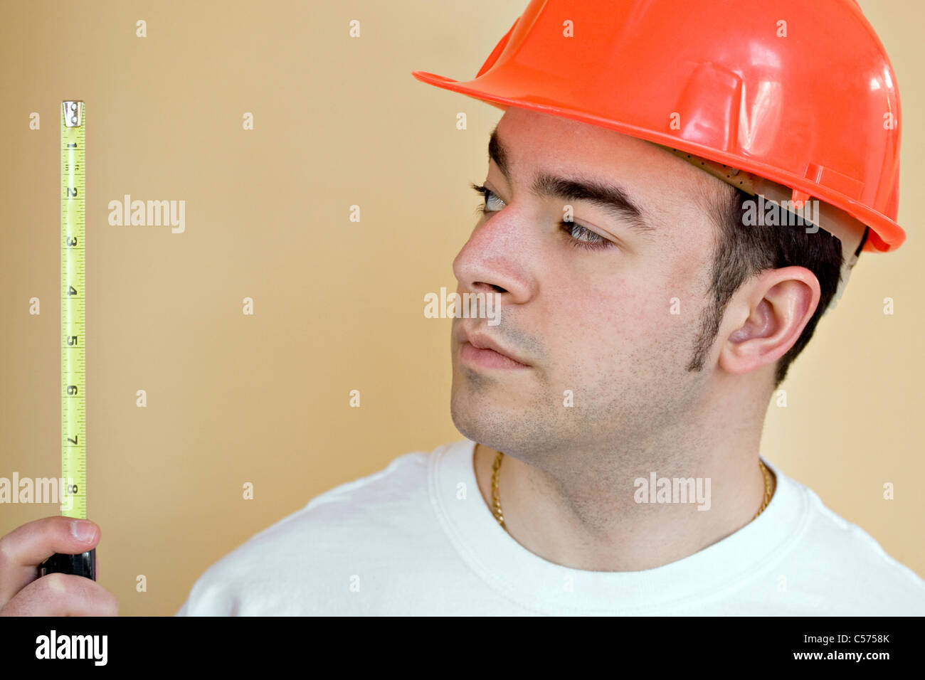 Ein junger Bauarbeiter mit einem Maßband. Es gibt viele Exemplar. Stockfoto