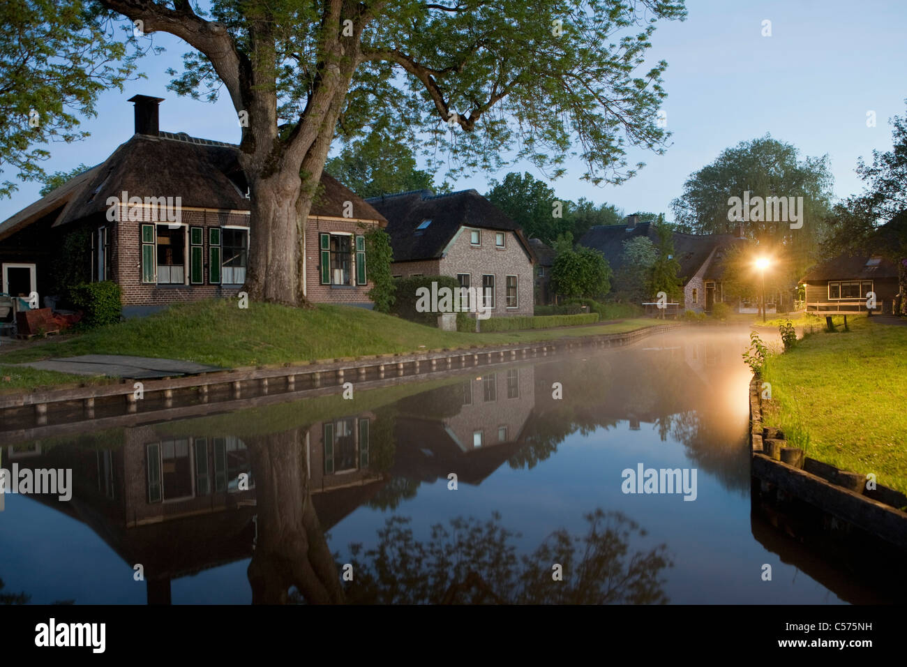 Die Niederlande, Dwarsgracht, in der Nähe von Giethoorn. Dorf mit fast nur Wasserstraßen. Häuser in der Morgendämmerung. Stockfoto