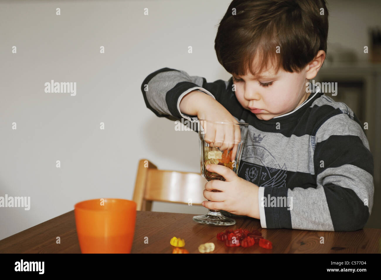 Junge mit Süßigkeiten am Tisch spielen Stockfoto