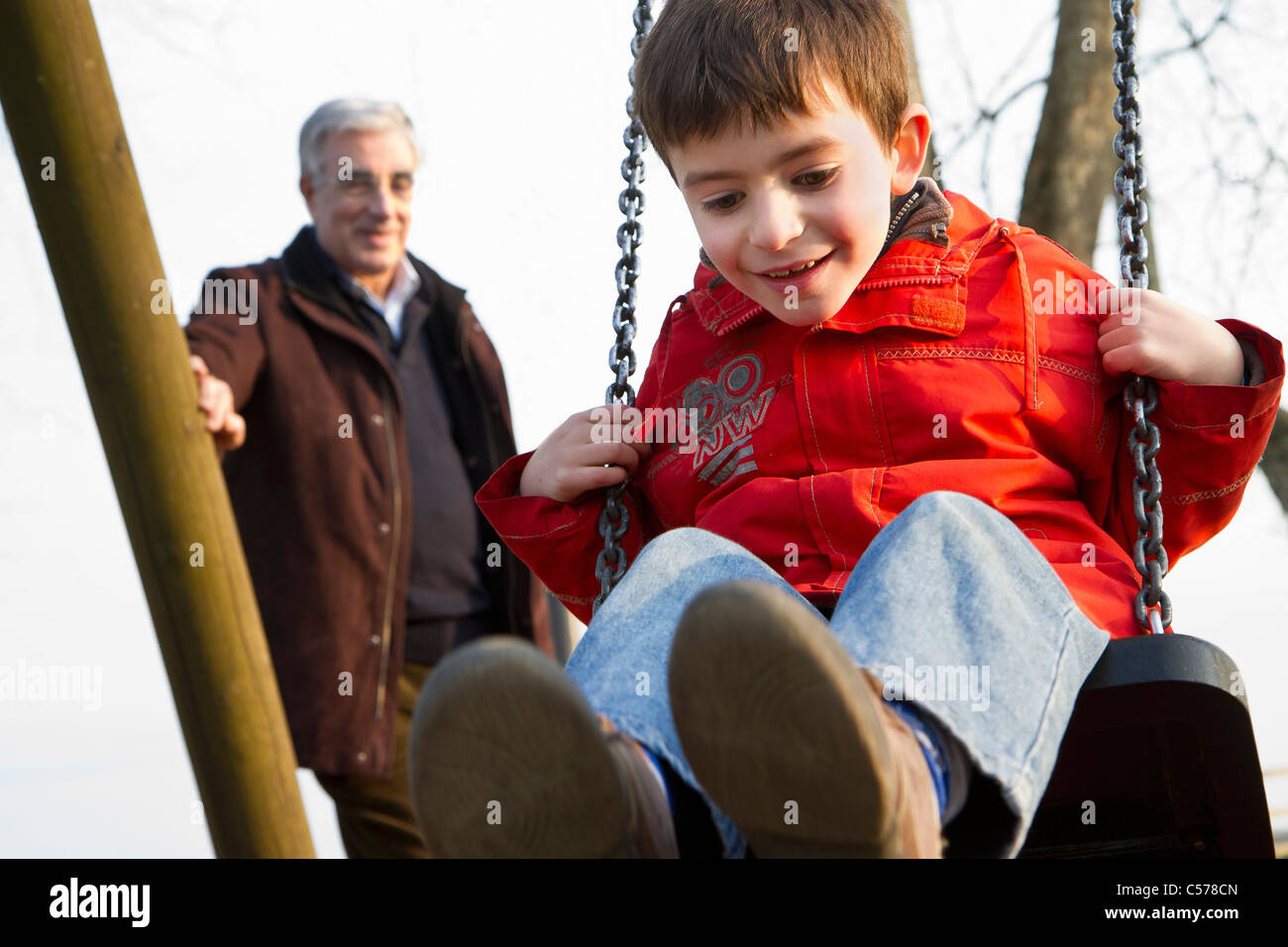 Mann schob Enkel auf Schaukel im park Stockfoto