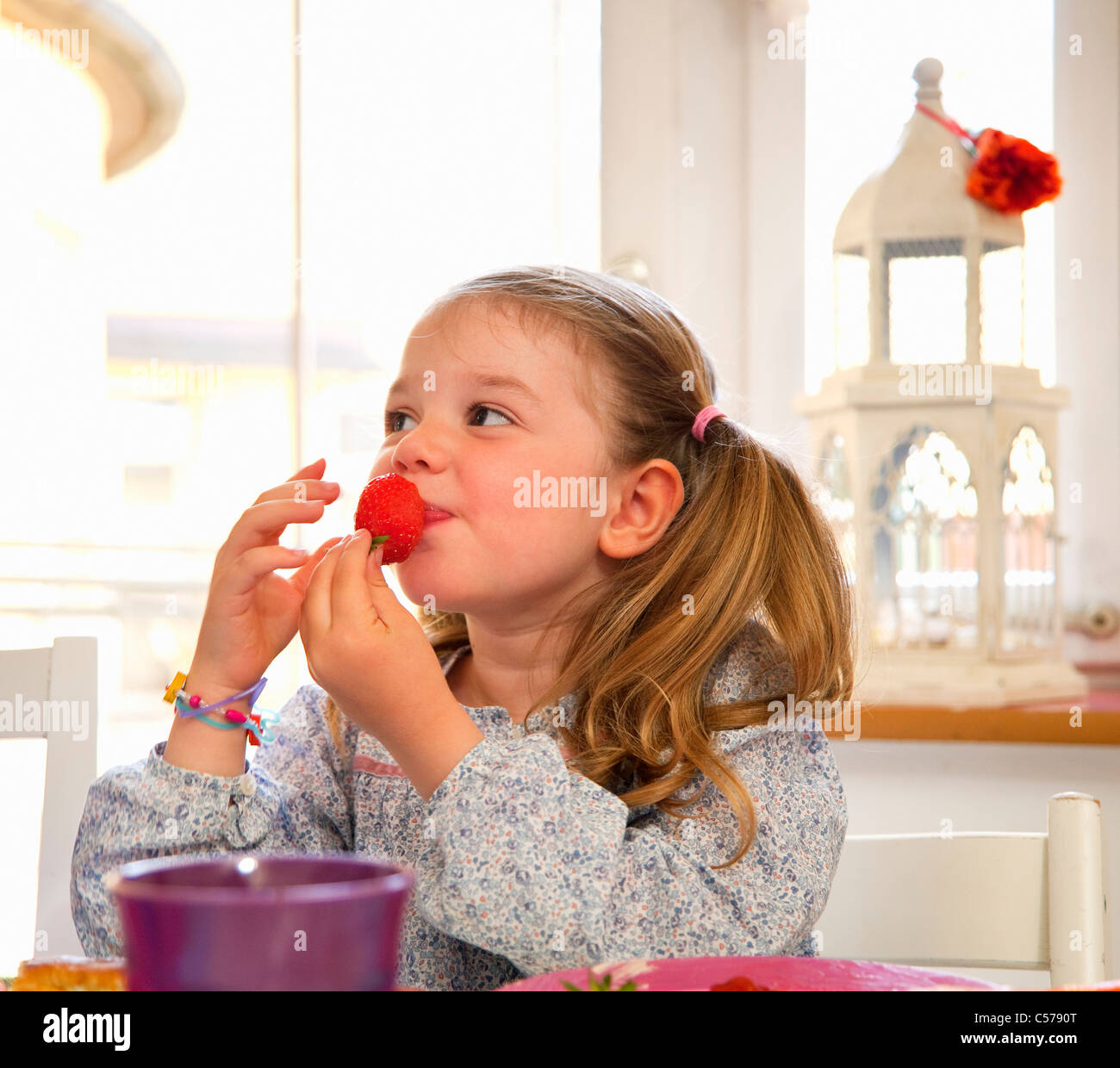 Mädchen eine Erdbeere am Tisch essen Stockfoto