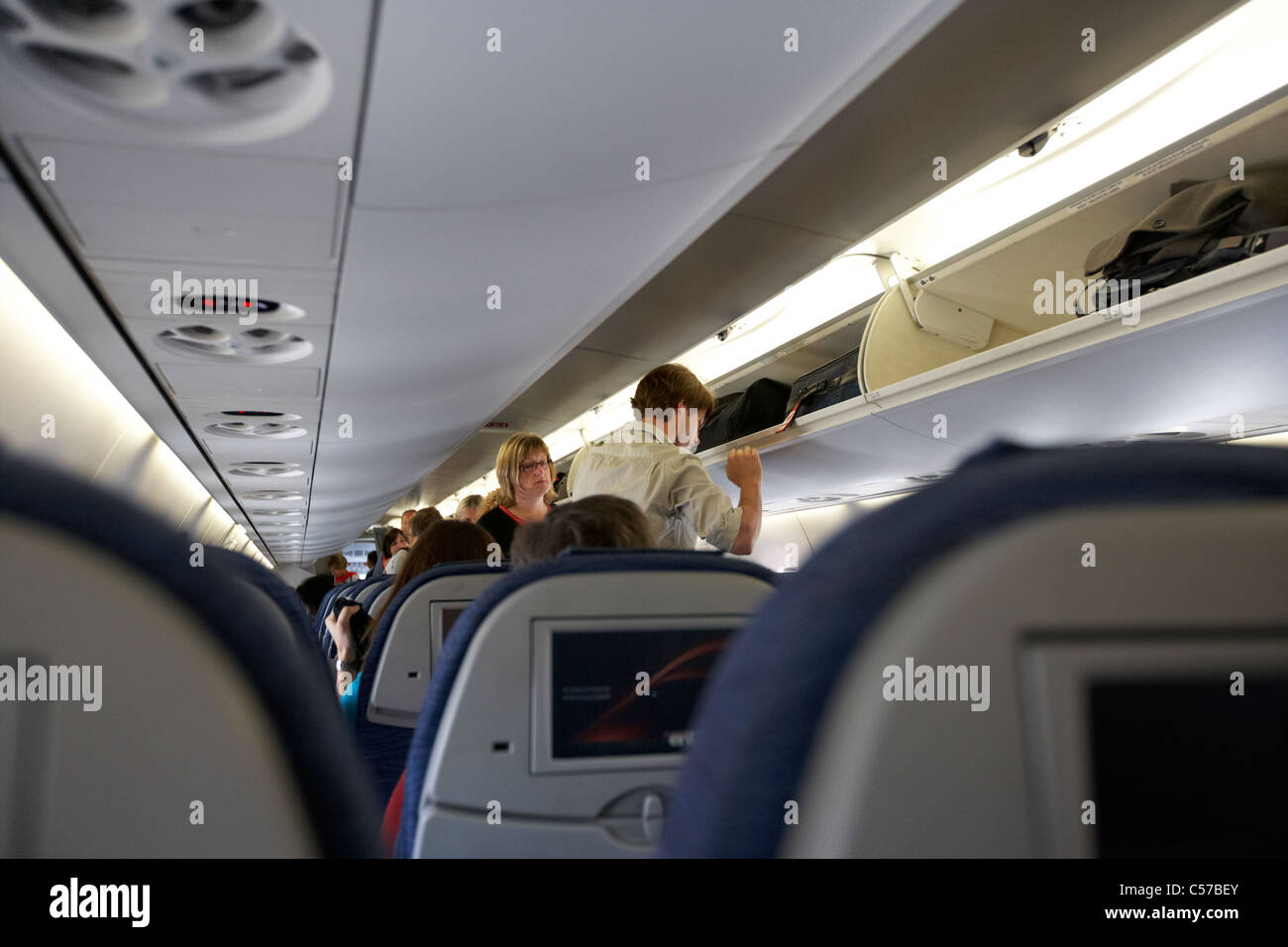 Passagiere an Bord einer Air Canada Embraer emb190 Passagierflugzeug warten auf Mann, Gepäck im Gepäckfach Stockfoto