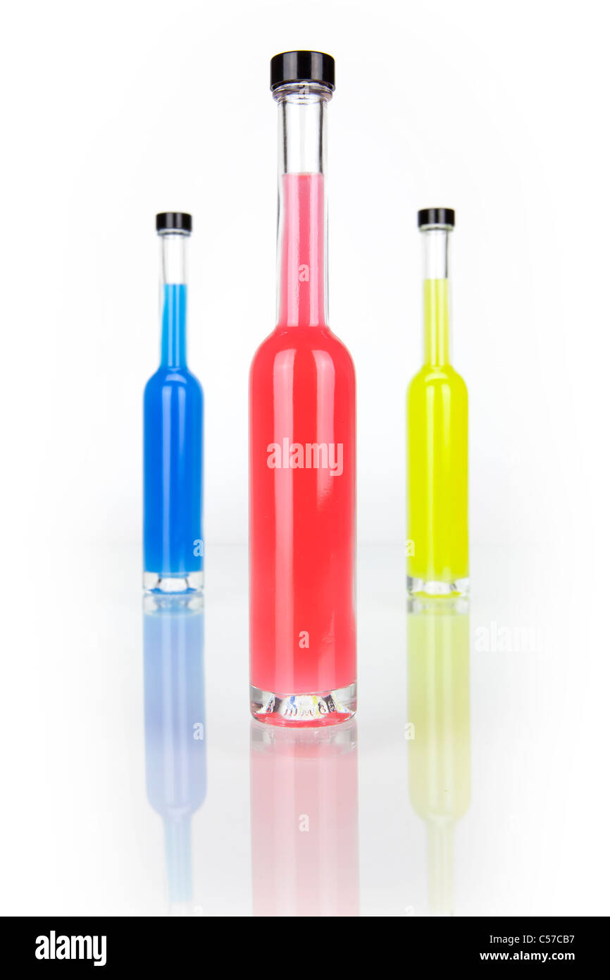 drei Glasflaschen mit farbigen Getra ¤ Nken in rot, blau, gelb Stockfoto