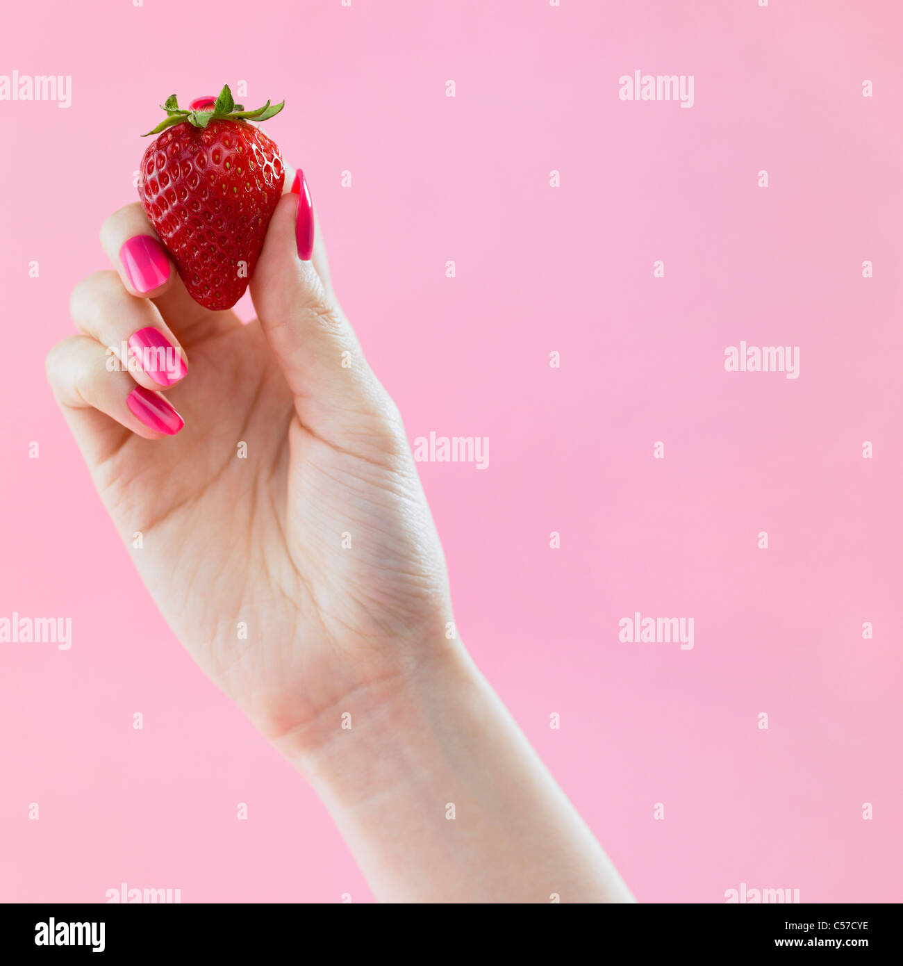 rosa farbigen Nagel Hand greifen die Erdbeere Stockfoto