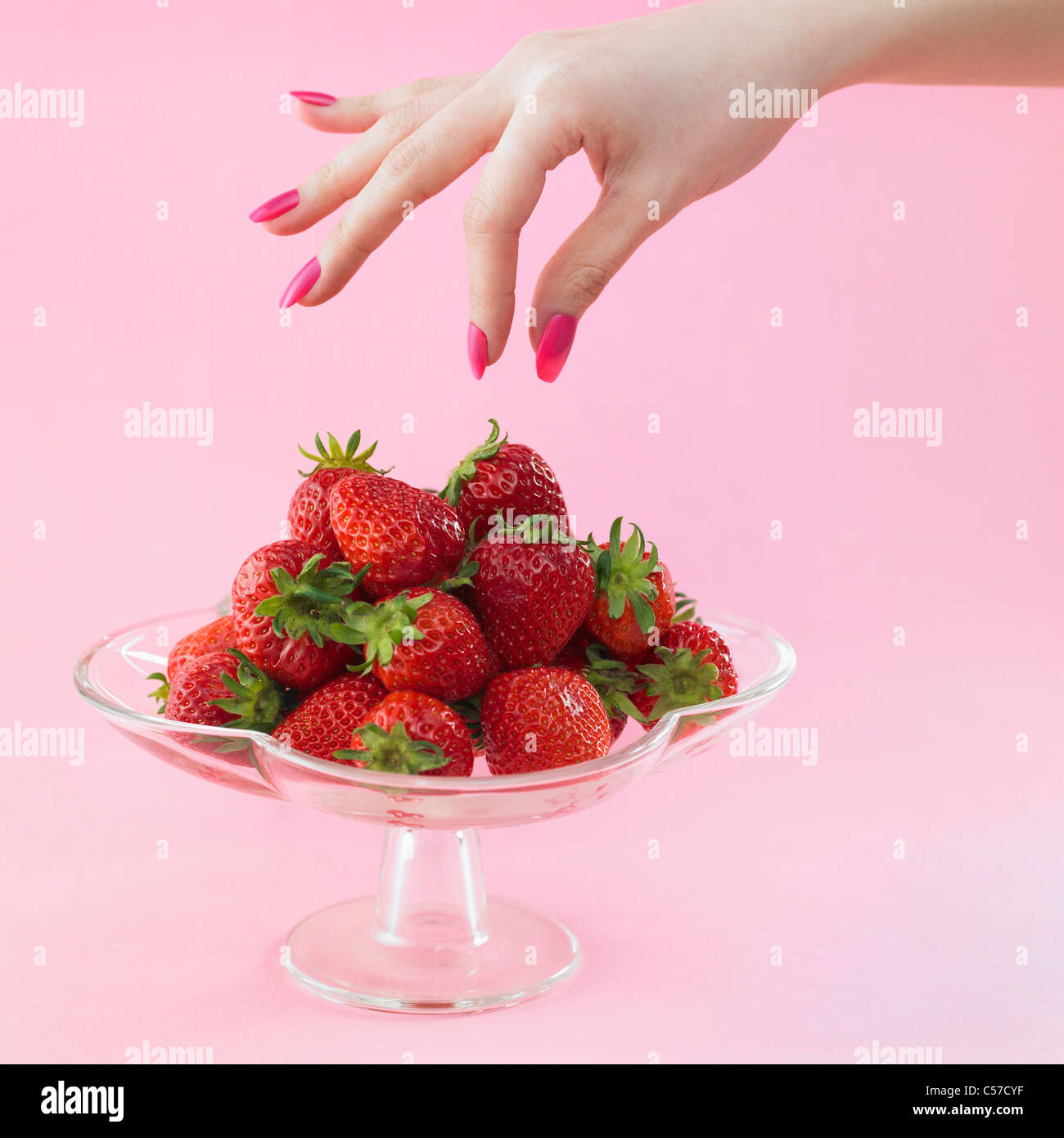 rosa farbigen Nagel Hand und Erdbeeren Stockfoto