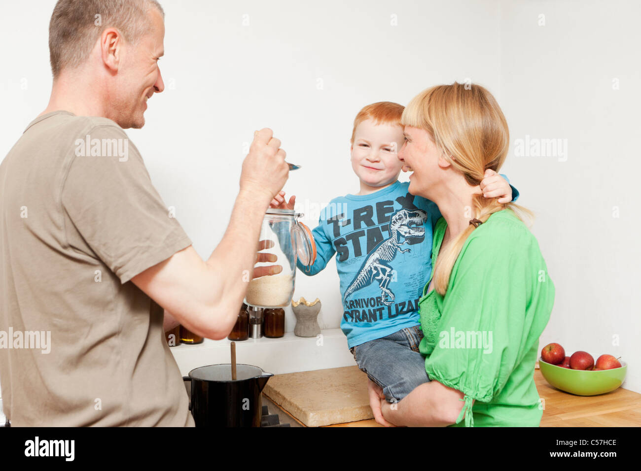 Eltern, die Fütterung nur ungern Sohn in Küche Stockfoto