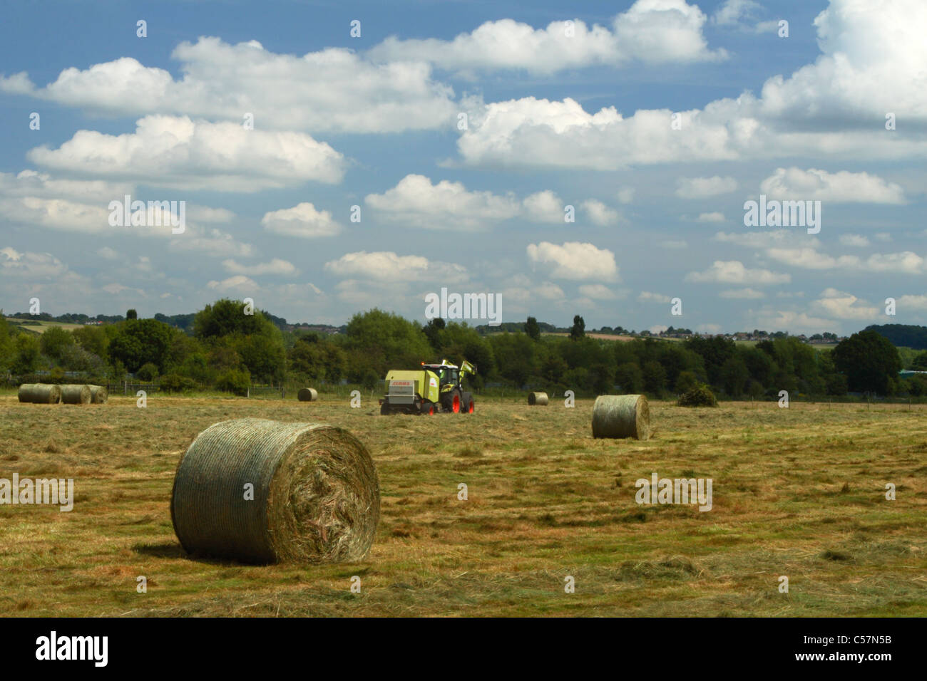 Ein Heu Ballenpresse Traktor arbeitet ein Feld in Bourne End in Buckinghamshire, Vereinigtes Königreich Stockfoto