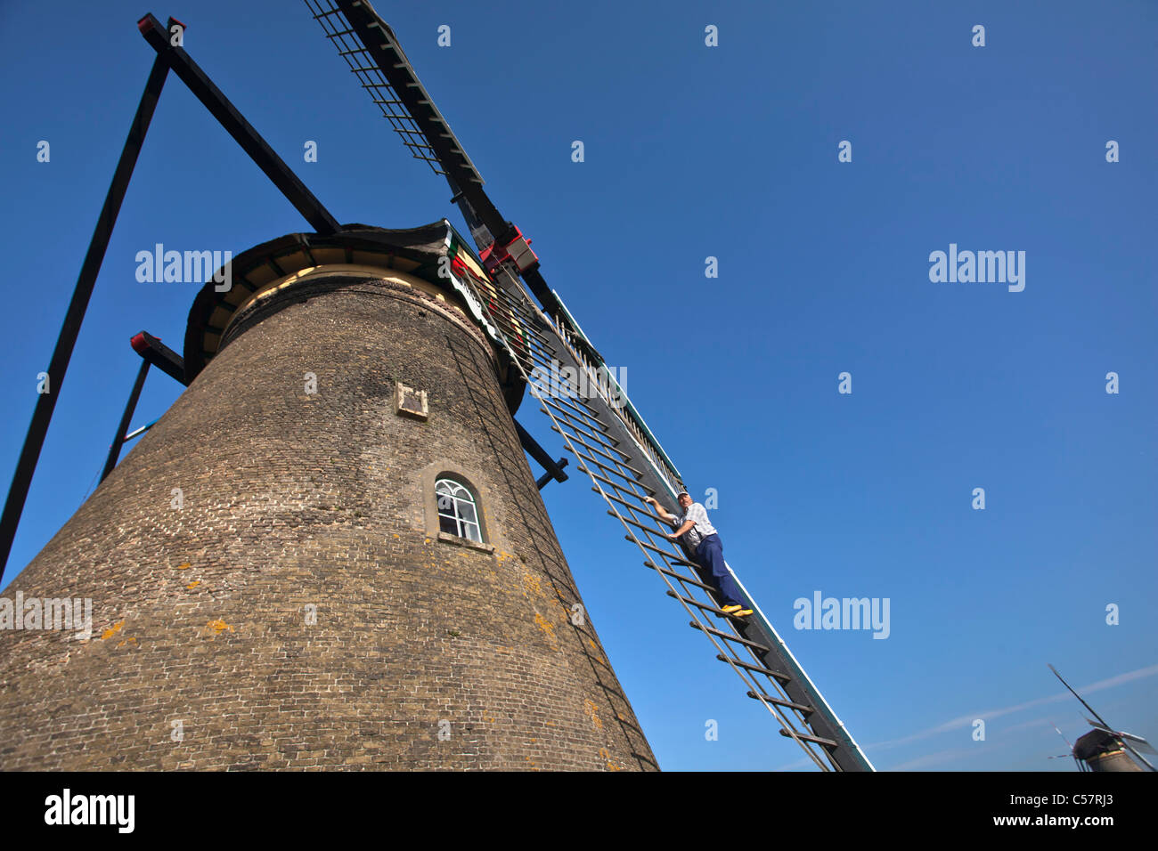 Die Niederlande, Kinderdijk, Windmühlen, UNESCO-Weltkulturerbe. Miller mit Holzschuhen auf Vane. Stockfoto