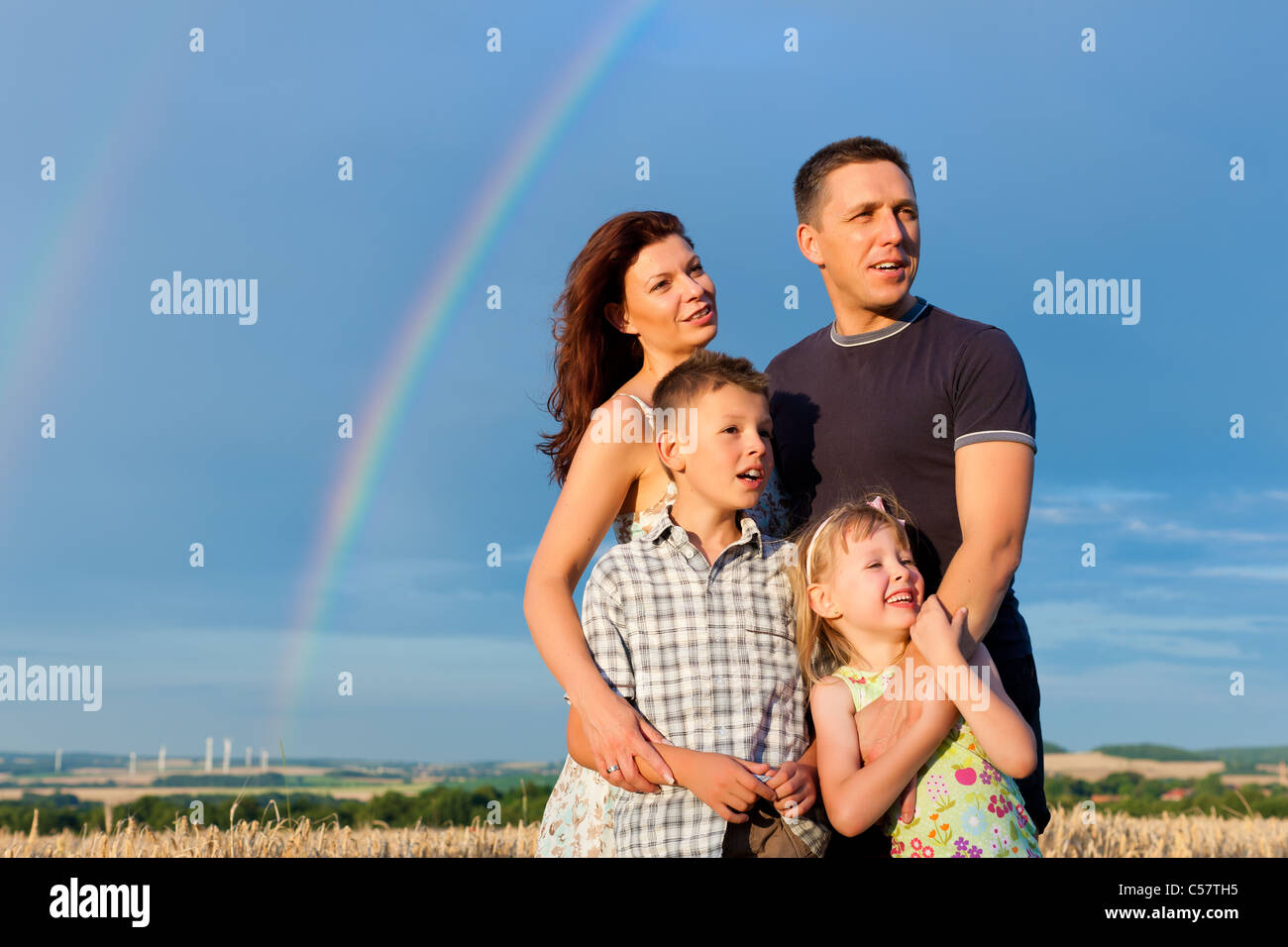 Glückliche Familie - Mutter, Vater, Kinder - stehen unter einem Regenbogen im Sommer Blick in eine glorreiche Zukunft Stockfoto