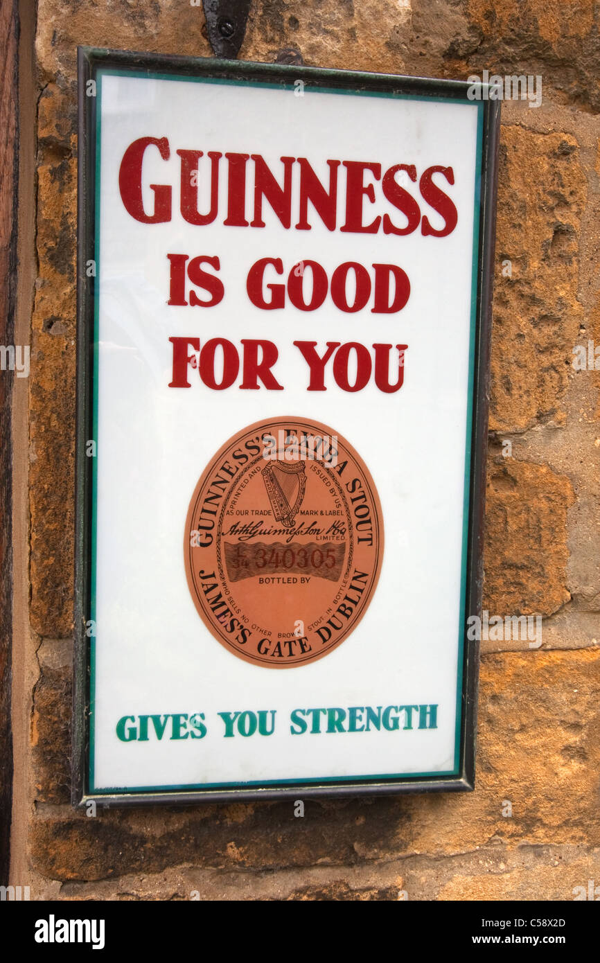 Guinness-Werbeschild an Wand vor Geschäft in Broadway, Worcestershire Stockfoto