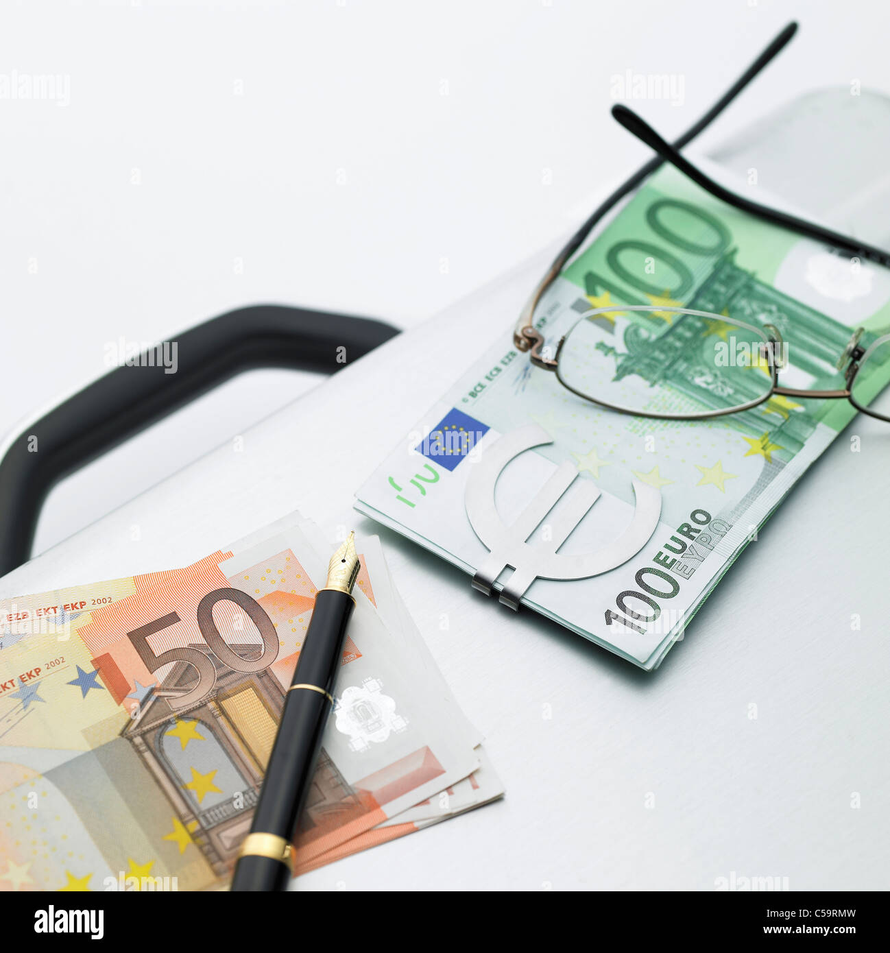 Nahaufnahme von Brillen mit Euro und einem Tintenstift auf Koffer Stockfoto