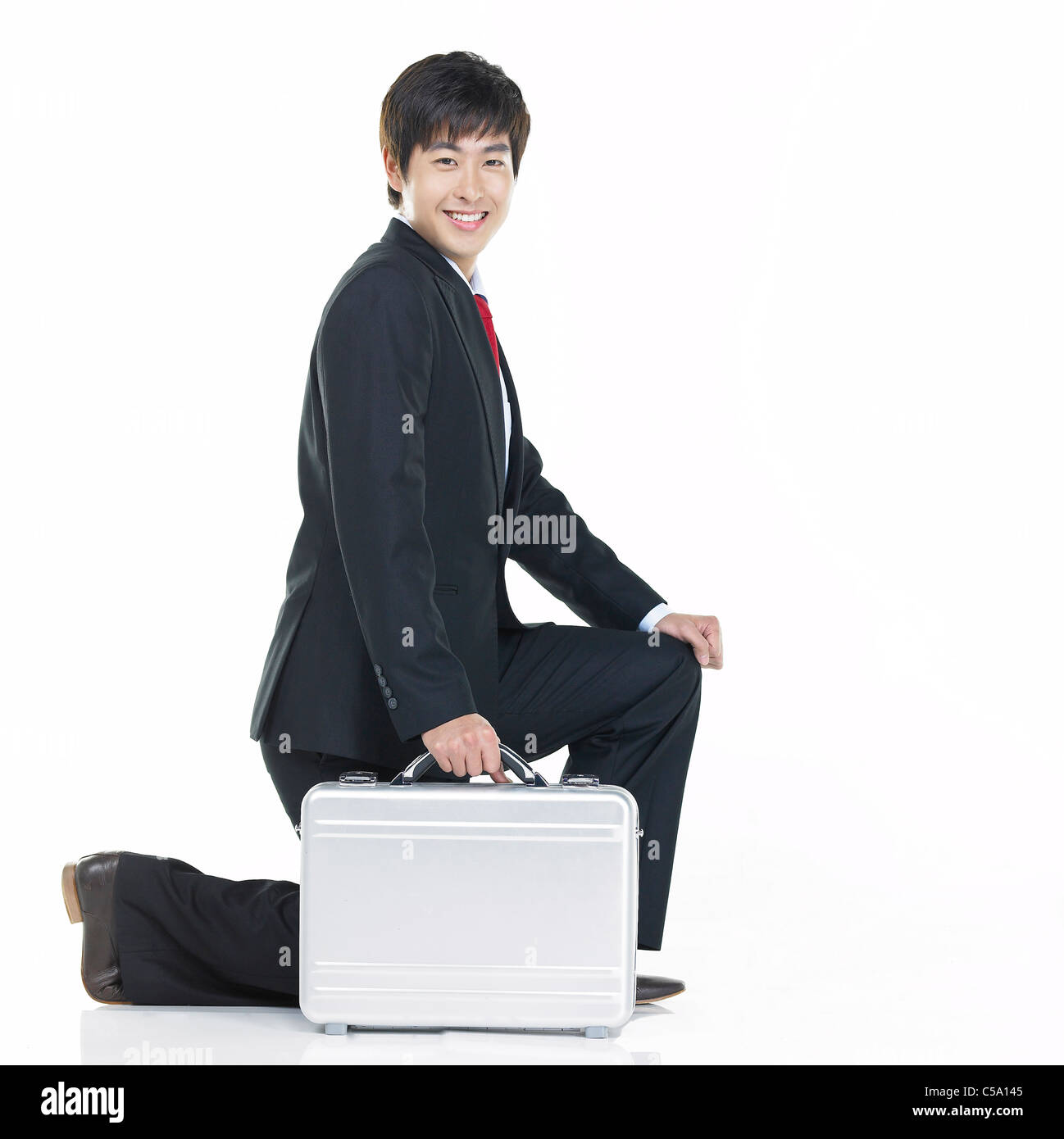 Porträt des Kaufmanns kniend, mit Koffer Stockfoto