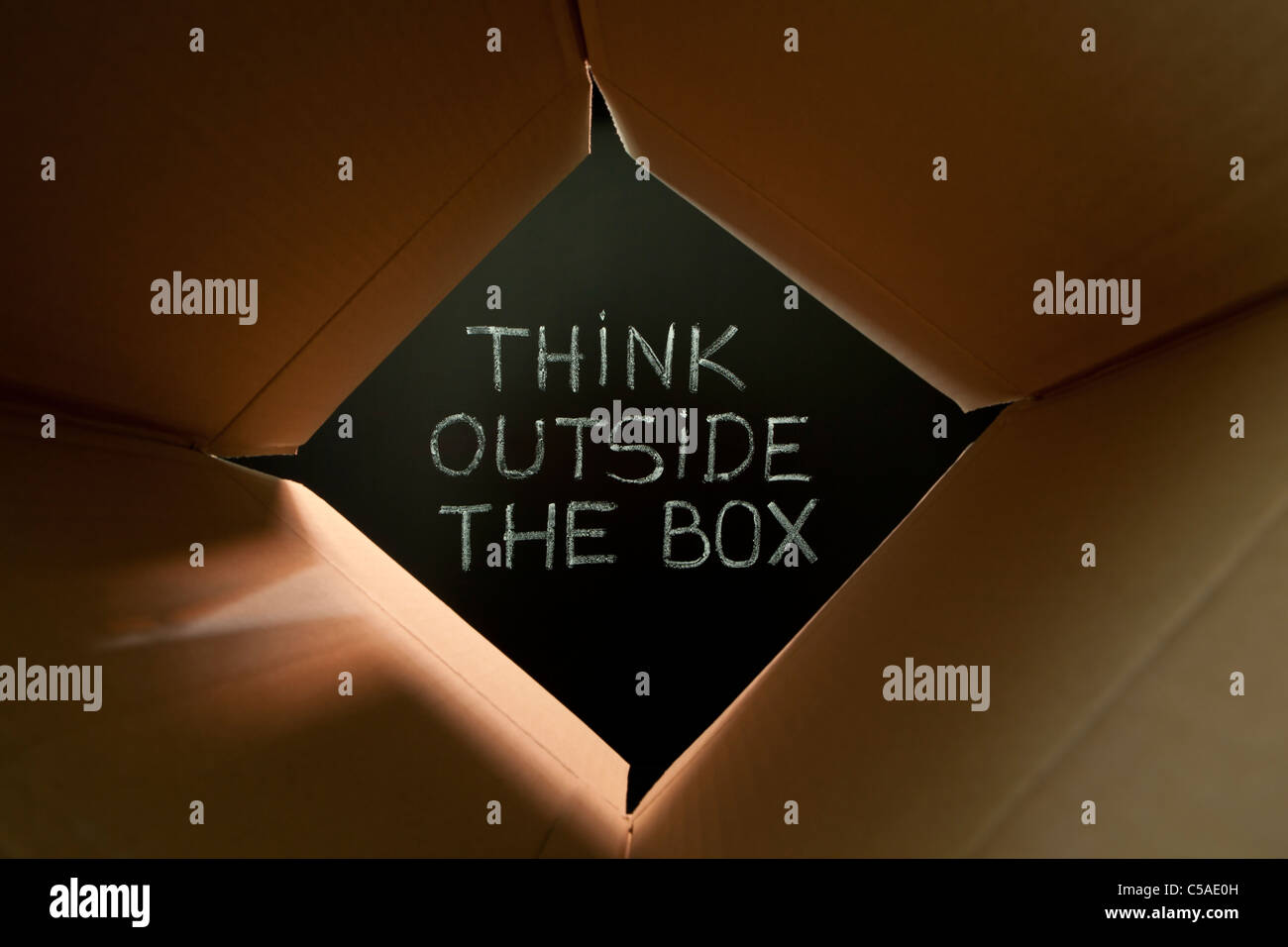 Konzept-Bild über das unkonventionelle oder anders denken. "Think outside the Box" handschriftlich mit weißer Kreide auf eine Tafel. Stockfoto