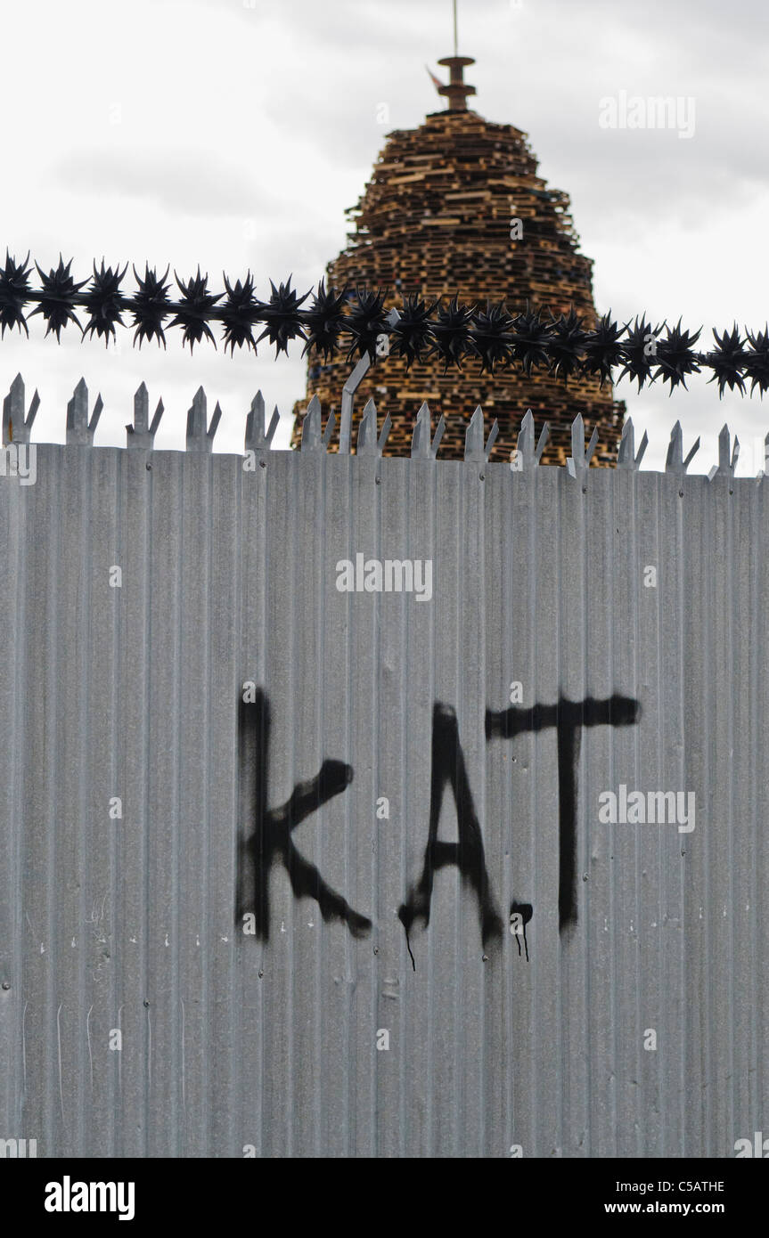 Sektiererische Graffiti auf einem Zaun in Belfast. KAT = töten alle Taigs (Katholiken) mit einem großen Lagerfeuer hinter Stockfoto