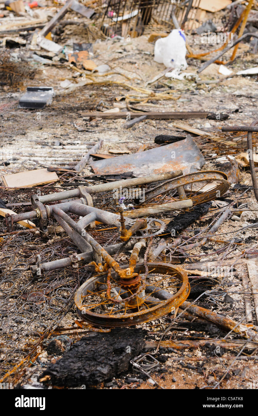 Verschiedene Objekte, darunter eine Fahrrad, das nach einem Brand in der Asche liegen. Stockfoto