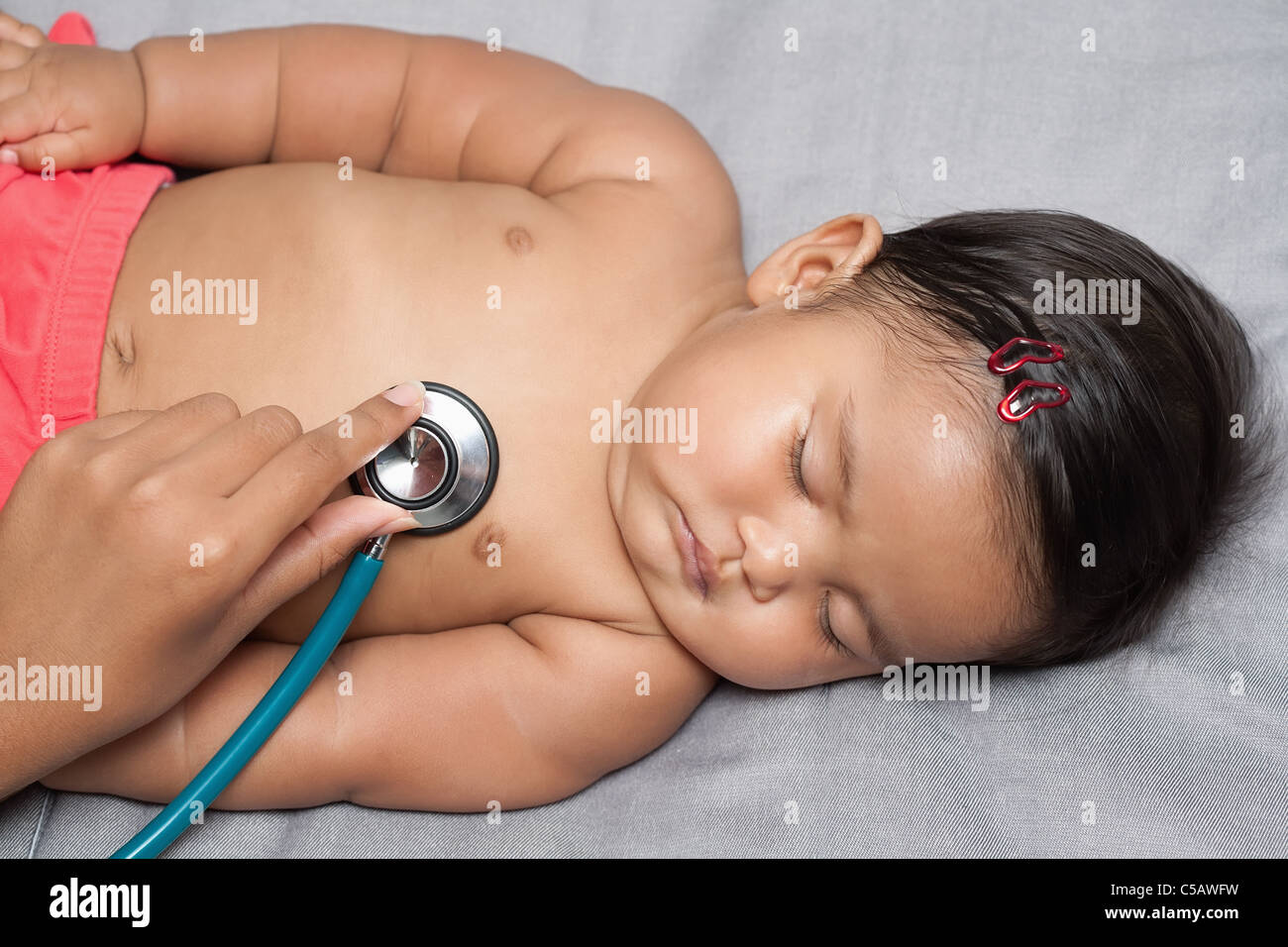 Schlafendes Baby Mädchen erhalten einen Herzschlag Untersuchung mit Krankenschwestern Hand sanft Holding Stethoskop auf das Herz des Babys während der Health Check up Stockfoto