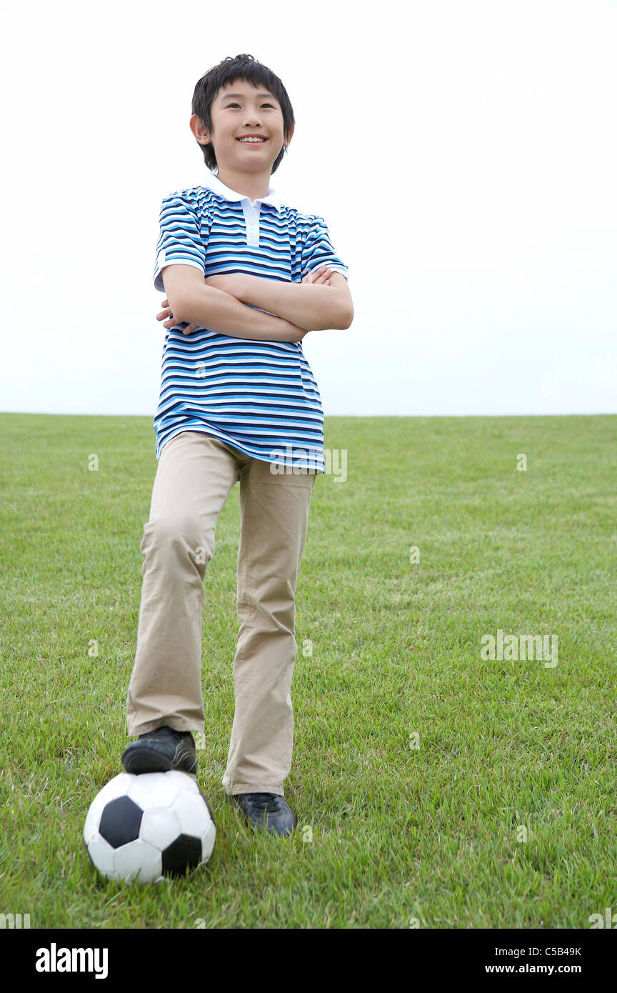 Junge stand auf Rasen mit Fuß auf Fußball Stockfoto