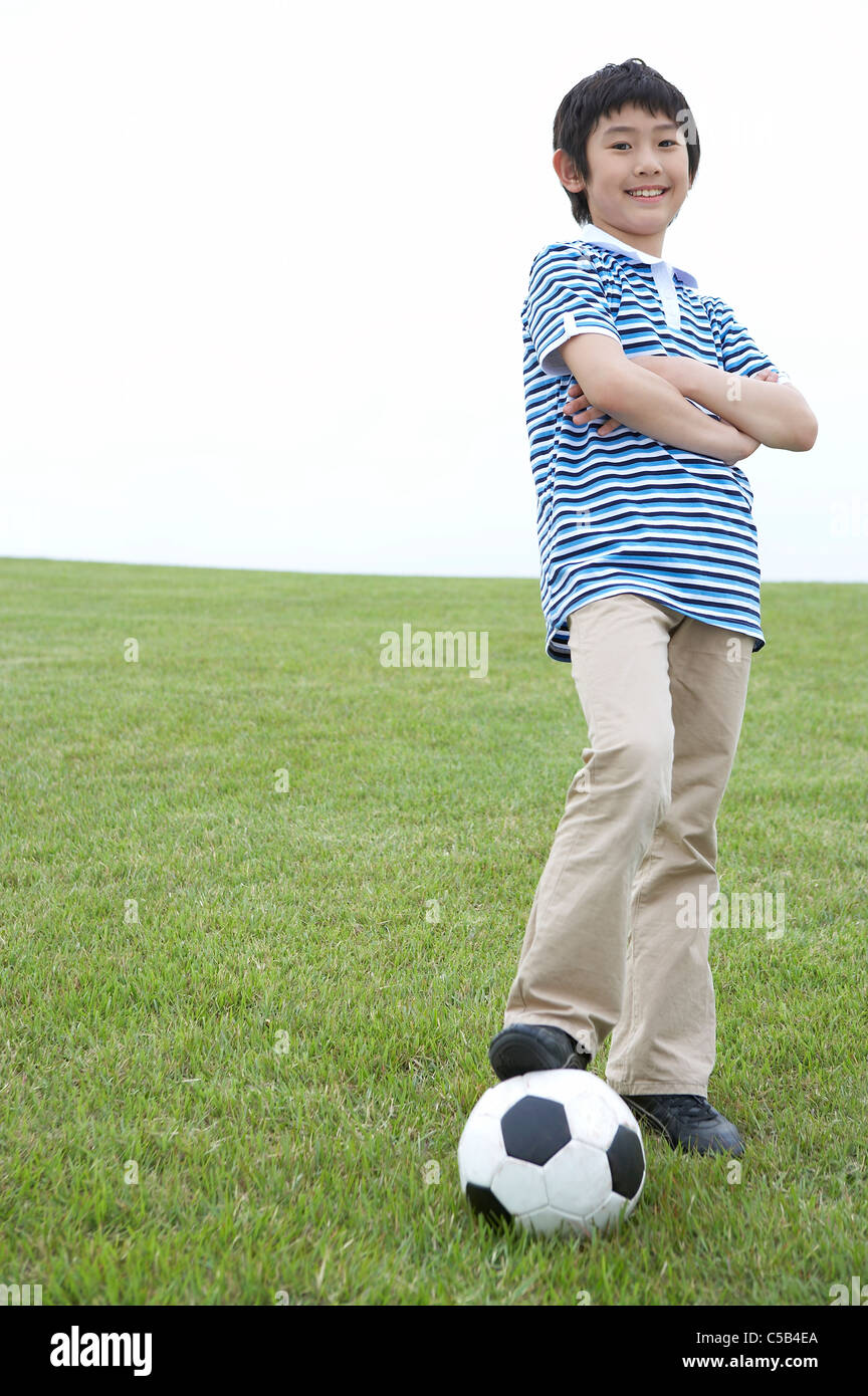 Junge stand auf Rasen mit Fuß auf Fußball Stockfoto