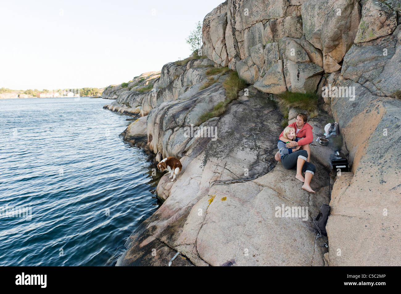 Romantische und entspannte Teenager-Jungen und Mädchen auf dem Felsen durch das ruhige Meer Stockfoto