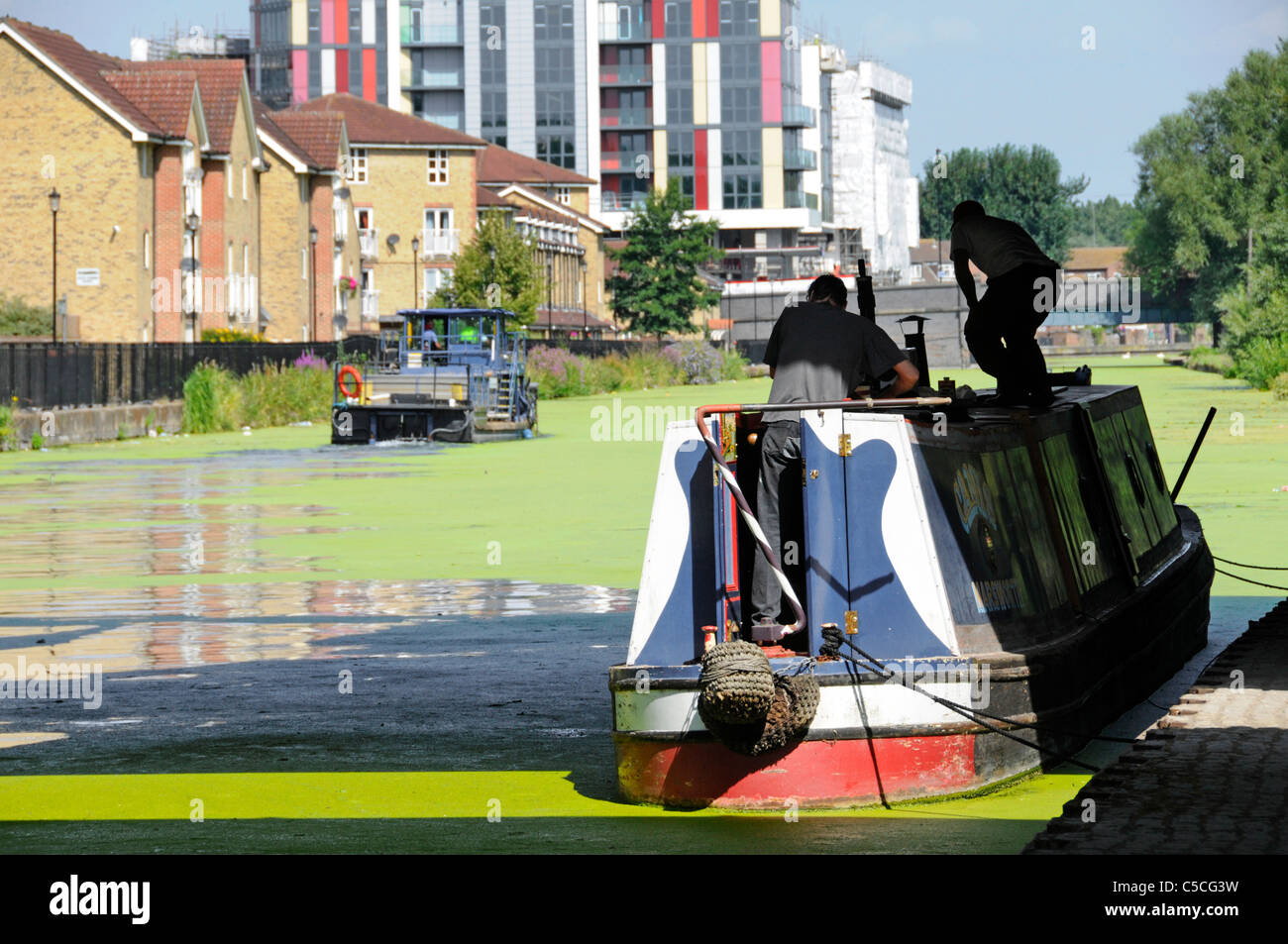 Nahaufnahme festgemacht Narrowboot auf der Lee Navigation mit britischen Wasserstraßen Maschine versucht, Sommer Algenblüte grünen Schleim zu schöpfen Hackney East London Großbritannien Stockfoto