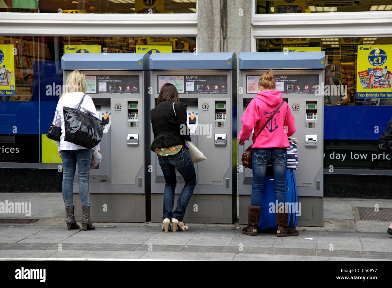 Drei junge Frauen, die Tickets für die Straßenbahn LUAS in Abbey Street, Zentrum von Dublin Stockfoto