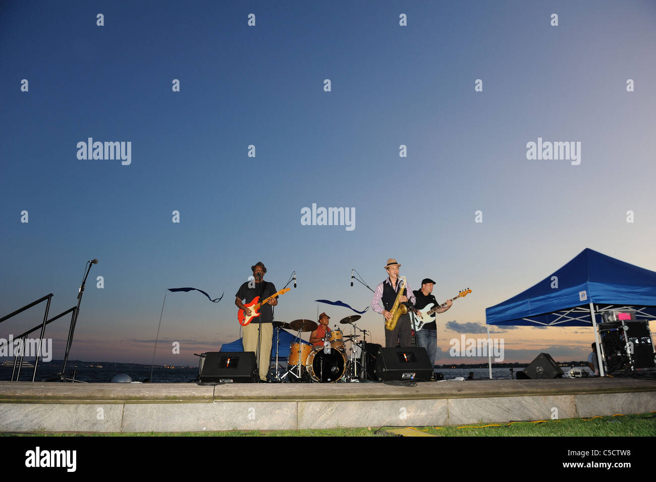 Irving Louis Lattin und seine Gruppe Blues in Battery Park City mit dem New Yorker Hafen im Hintergrund zu spielen. Stockfoto