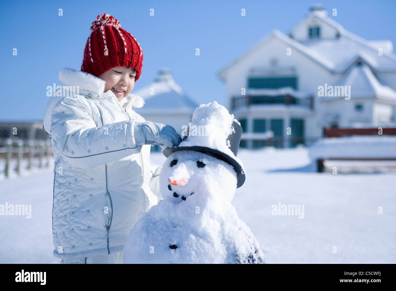 Mädchen stand neben der Schneemann Stockfoto