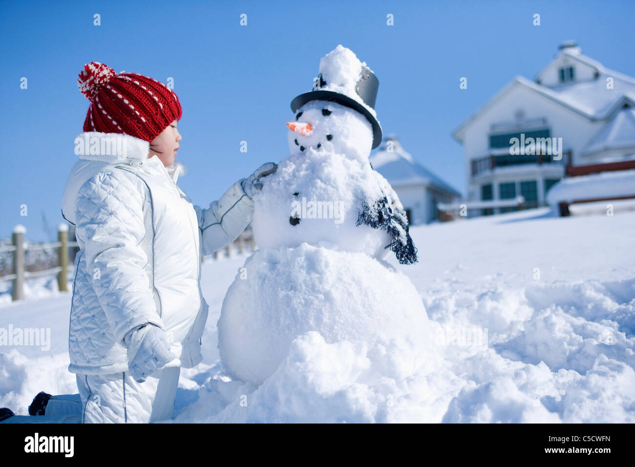 Mädchen ist neben der Schneemann Stockfoto