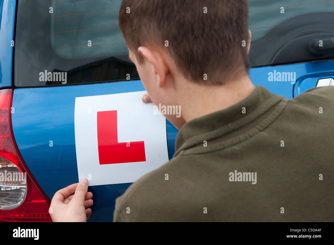 Teenager, die Festsetzung einer L-Platte auf der Rückseite von einem Renault Clio vor eine Fahrstunde. Stockfoto