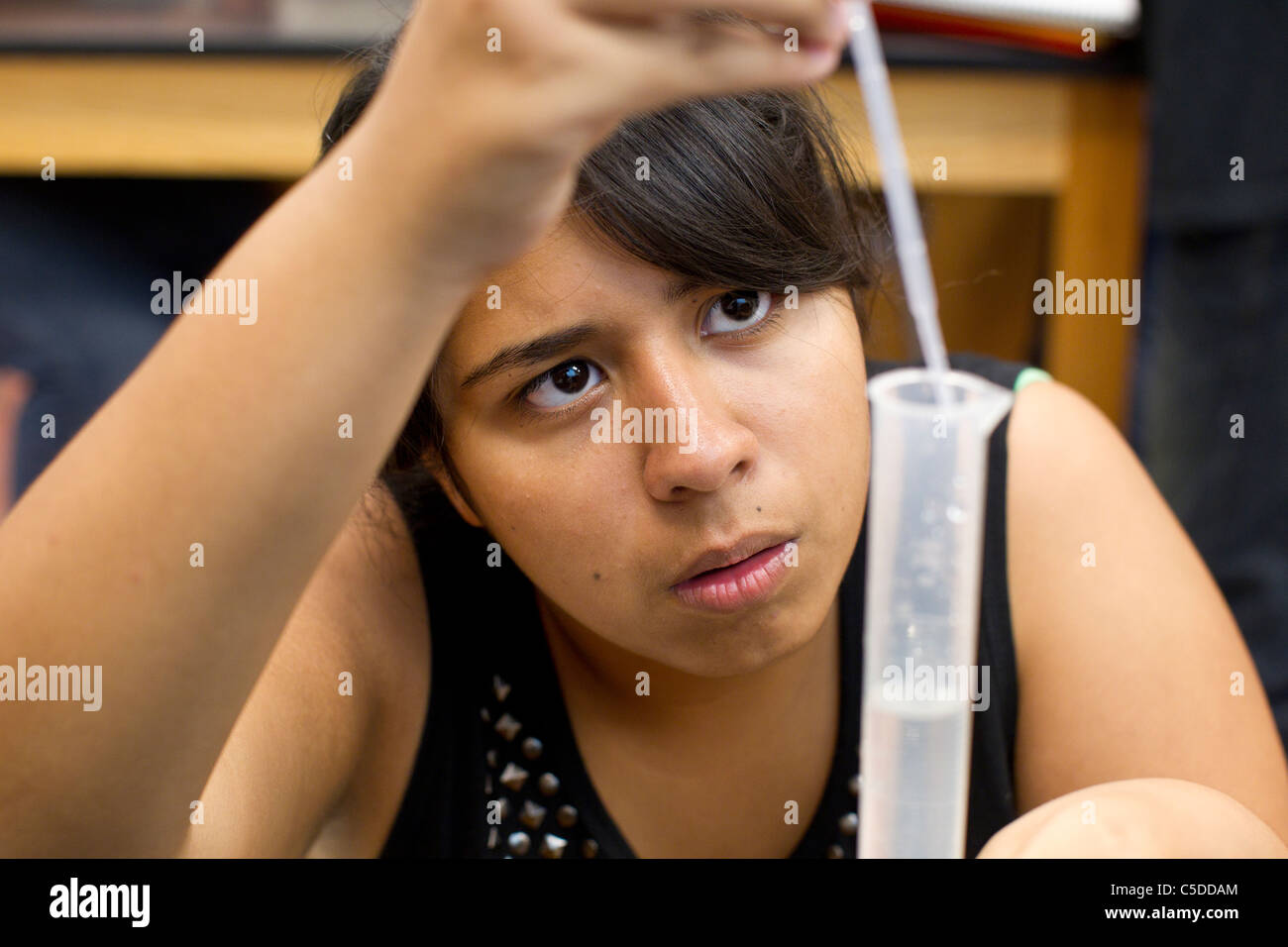 Hispanic weibliche High-School-Schüler misst Pipette Flüssigkeit in einen Messzylinder in High-School-Science-Lab-Klasse Stockfoto