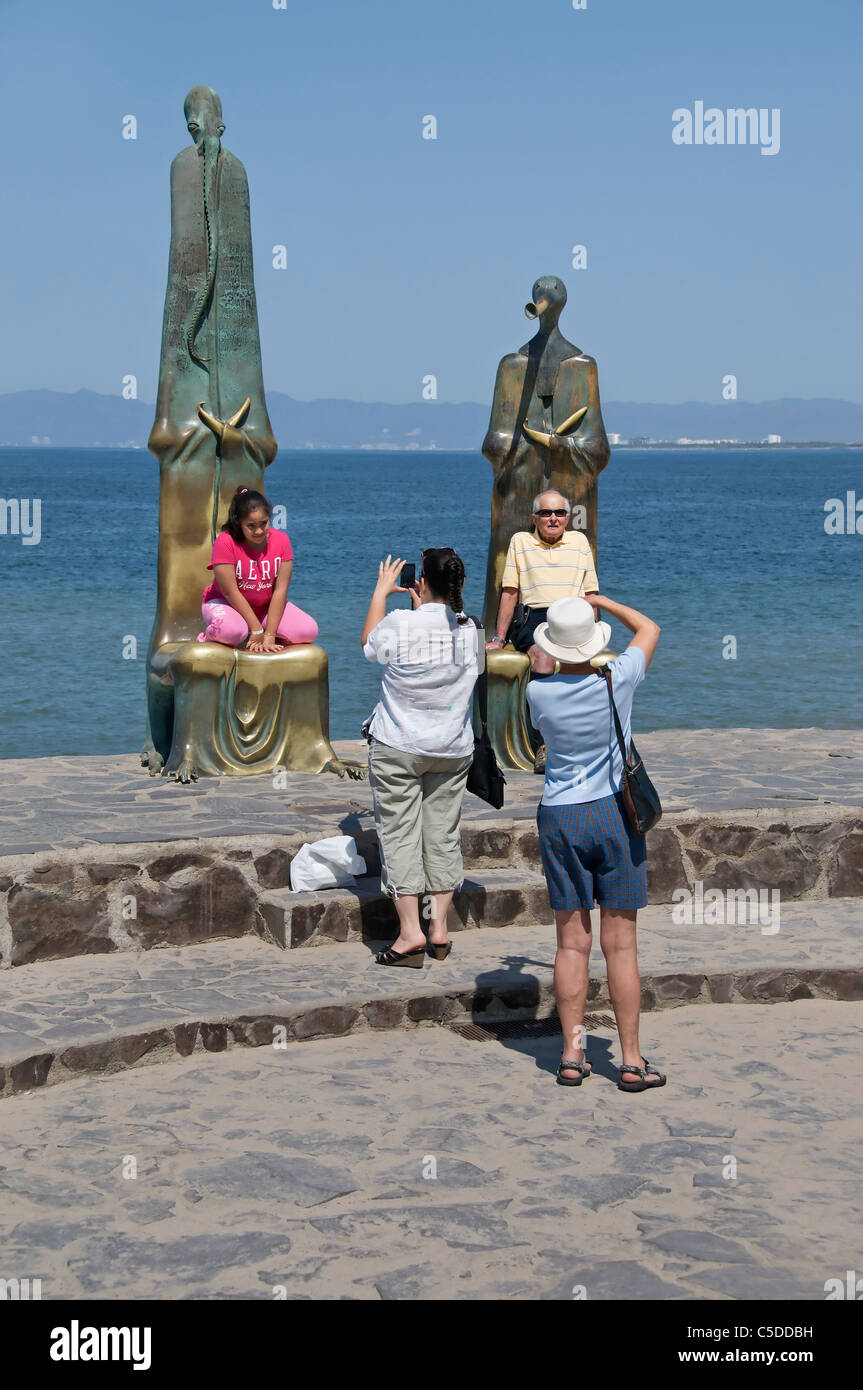 Touristen werfen durch das sitzen auf dem hochlehnigen abstrakte öffentlichen Skulpturen auf dem Malecon in Puerto Vallarta, Mexiko. Stockfoto