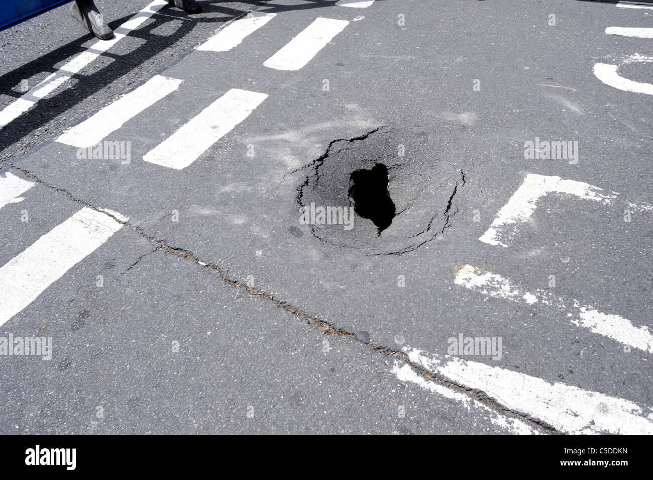 Eine Sicherheitsbarriere ist um ein Loch setzen, die plötzlich in eine stark befahrene Straße in Hove erschienen Stockfoto