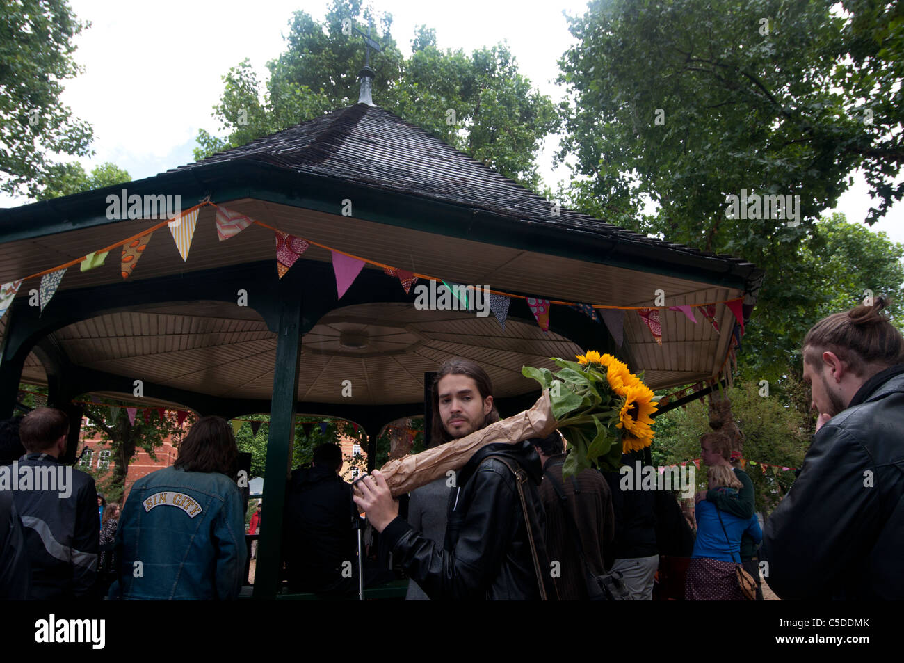 Arnold Circus Shoreditch, London Juli 2011. Mann mit Haufen von Sonnenblumen vor Musikpavillon. Stockfoto