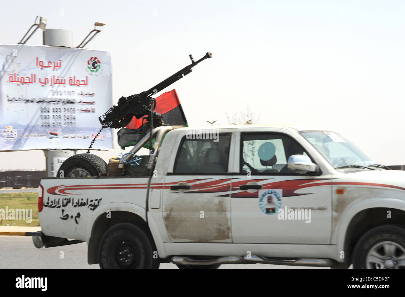 eine Pick up Truck fährt durch Bengasi auf dem Weg an die Front mit einer AAC-Pistole auf der Rückseite. Stockfoto